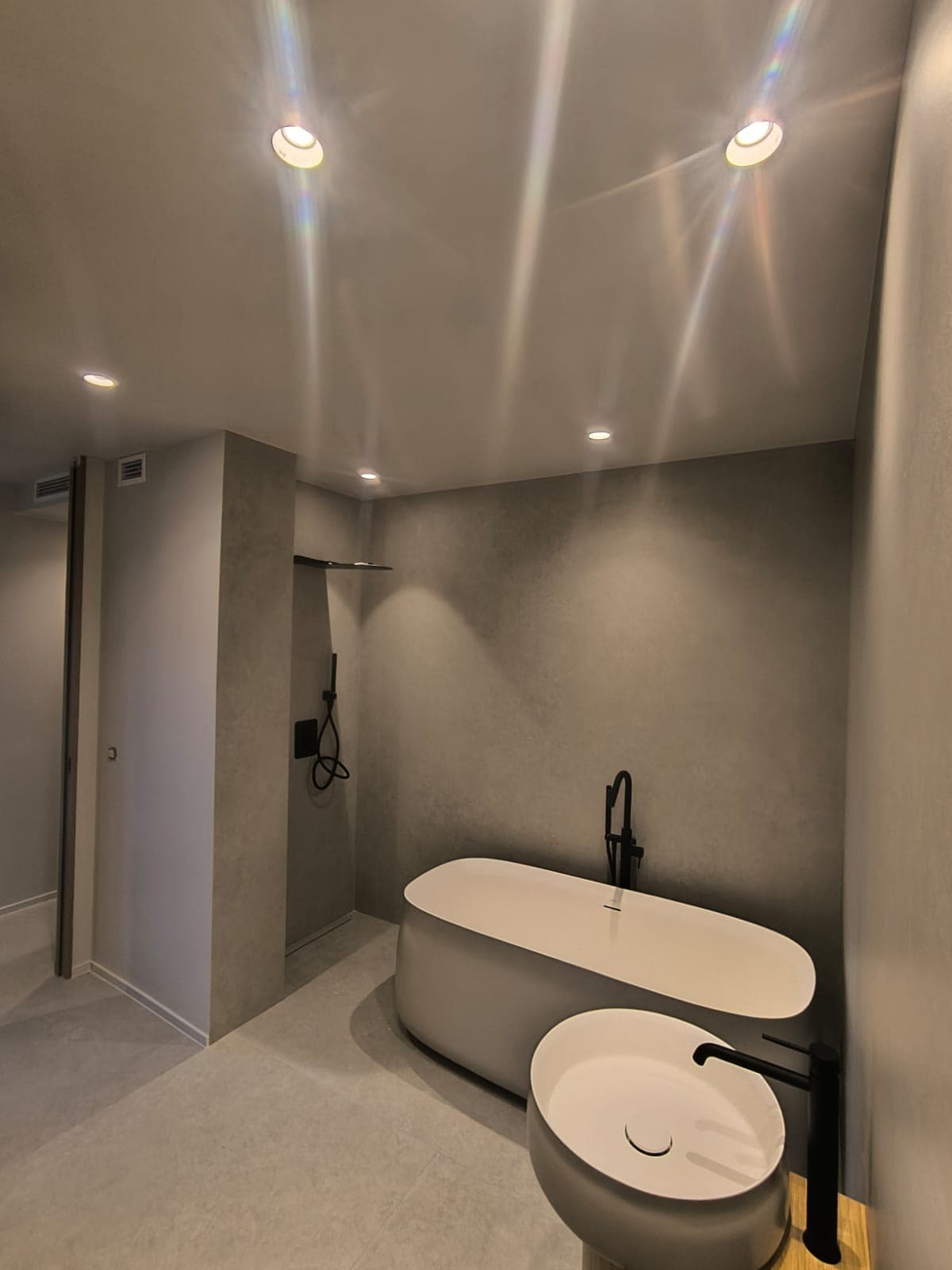 Suite con bañera exenta y microcemento reformada por Domus Lux