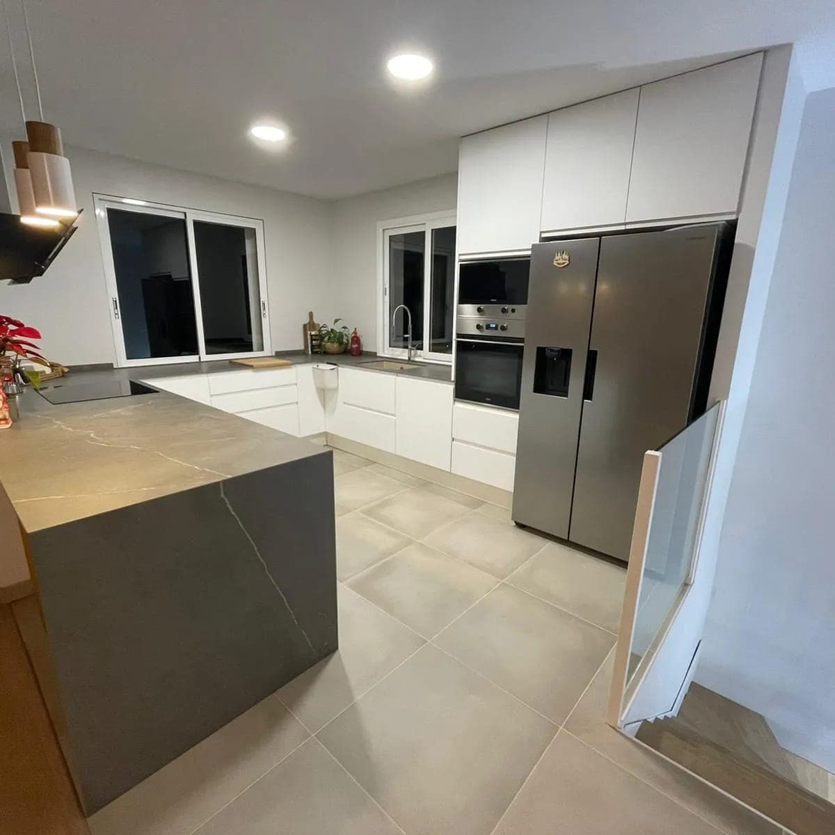 Cocina con isla de piedra y nevera americana reformada por Domus Lux
